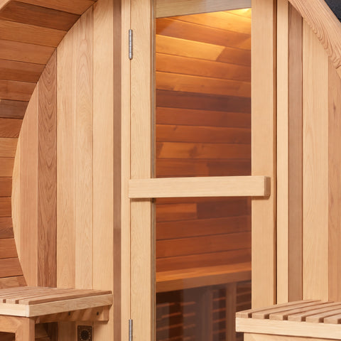 Close detail of the barrel sauna’s horizontal timber pull and timber-framed glass door.